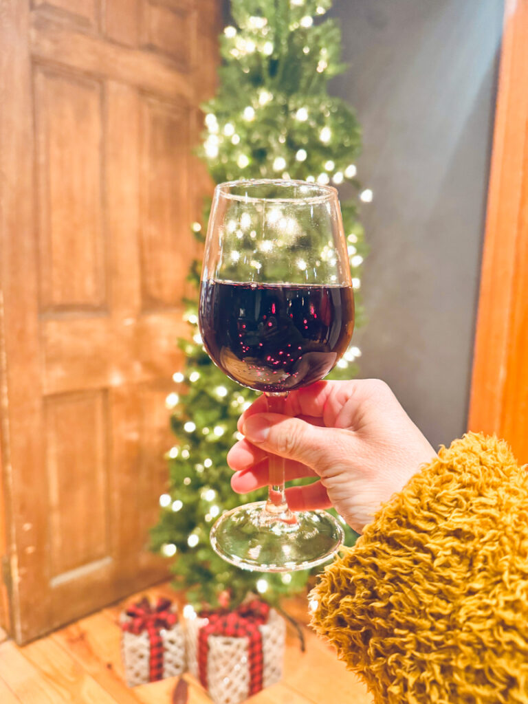 glass of wine in front of a christmas tree