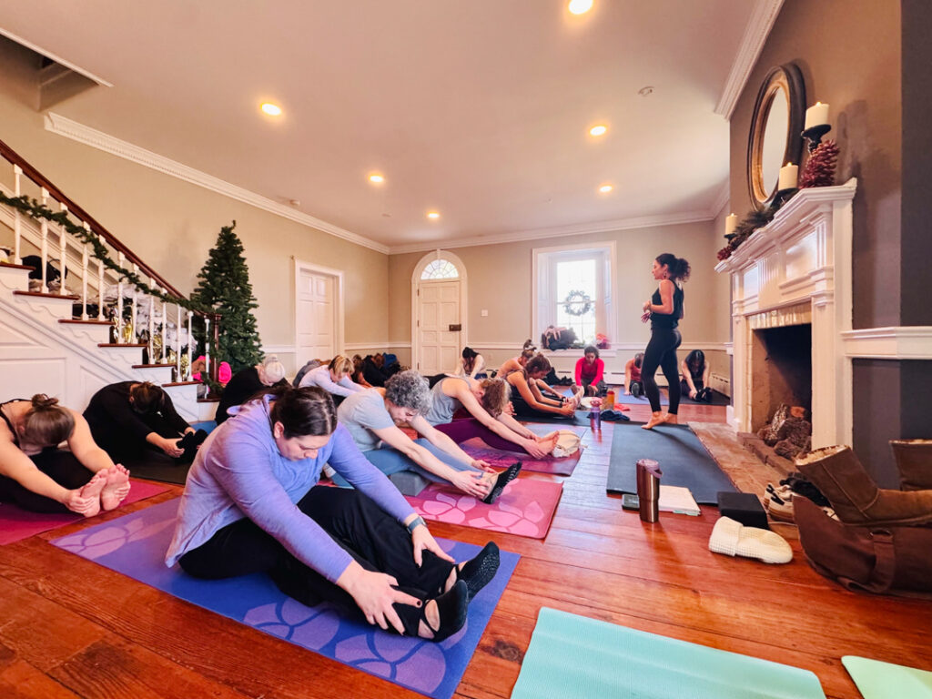 women doing yoga and touching their toes while sitting on their mats
